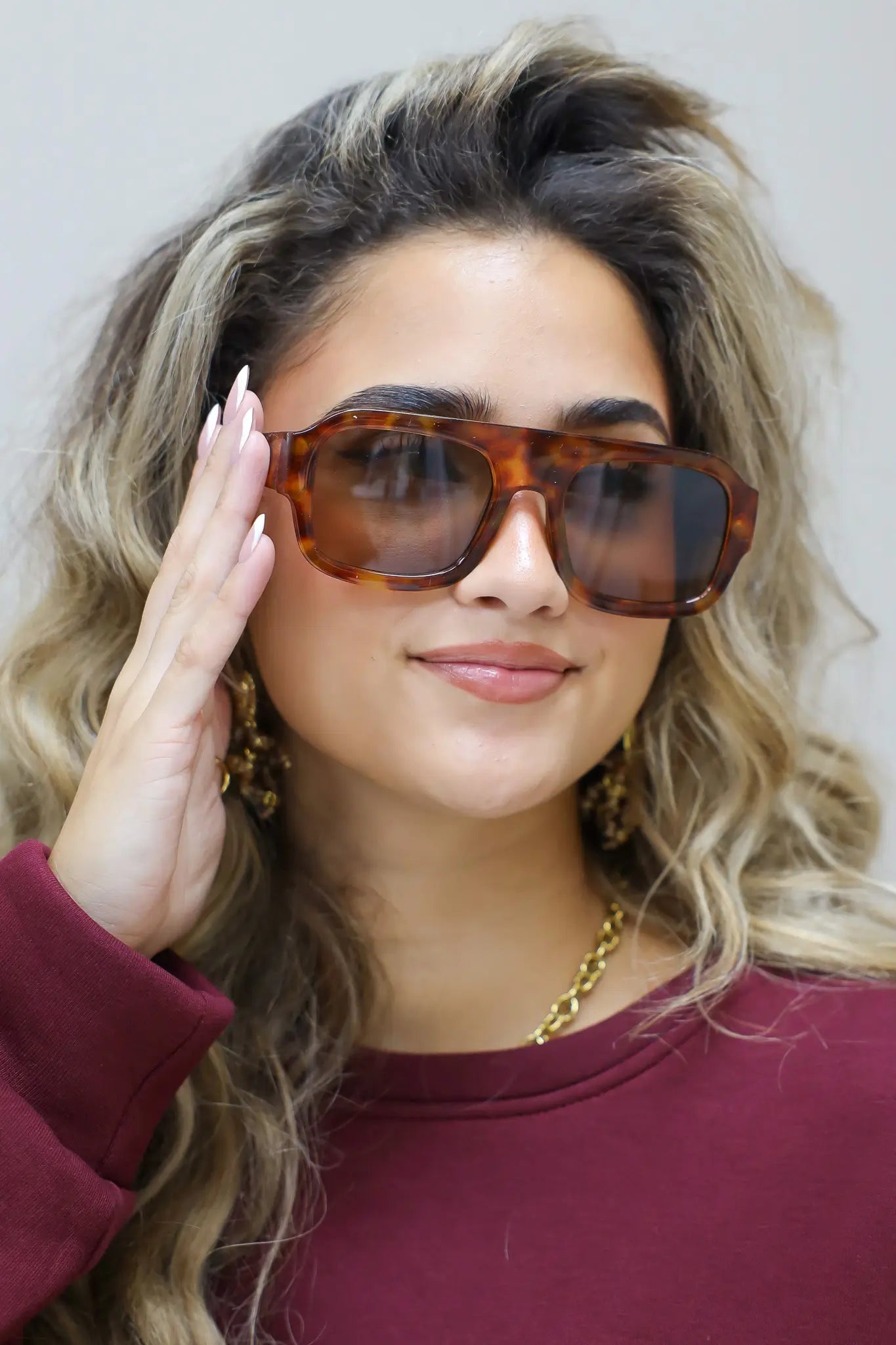 model met bruine zonnebril kijkt recht vooruit met los vallend haar