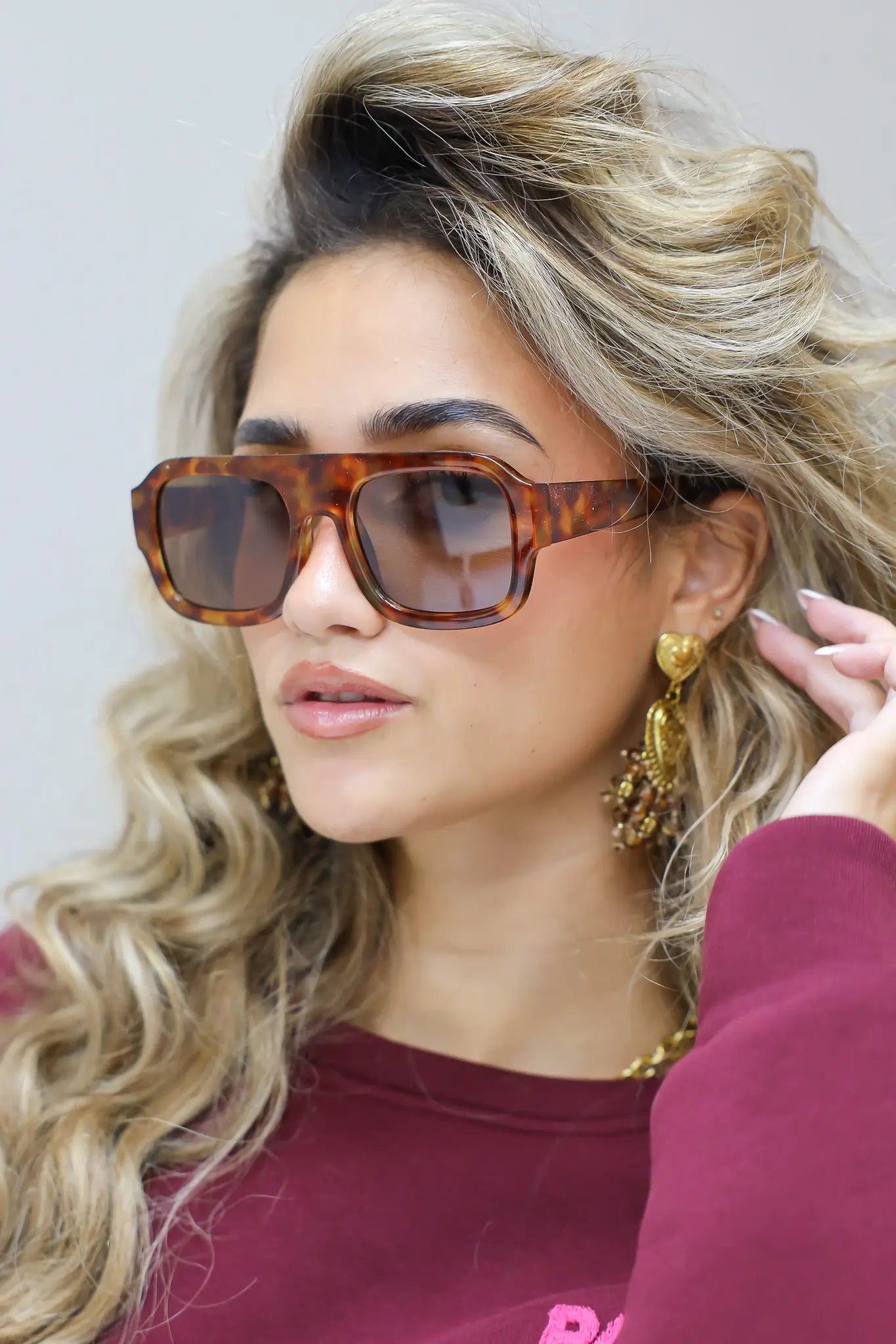 model met bruine zonnebril glimlacht licht richting camera