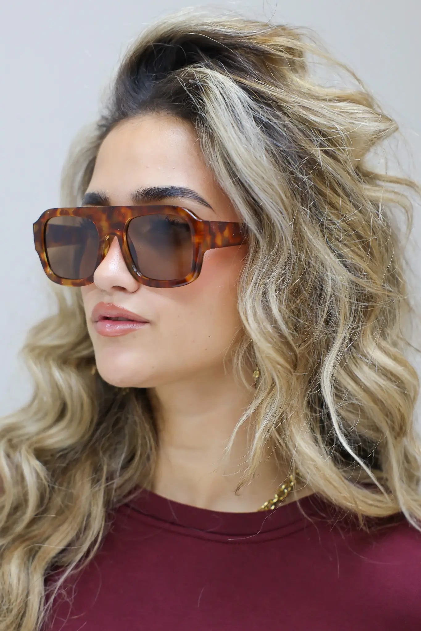 model raakt haar zonnebril aan en kijkt schuin omhoog