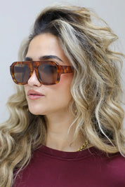 model raakt haar zonnebril aan en kijkt schuin omhoog