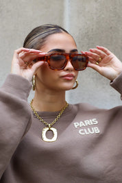 model tilt zonnebril iets omhoog en kijkt richting camera