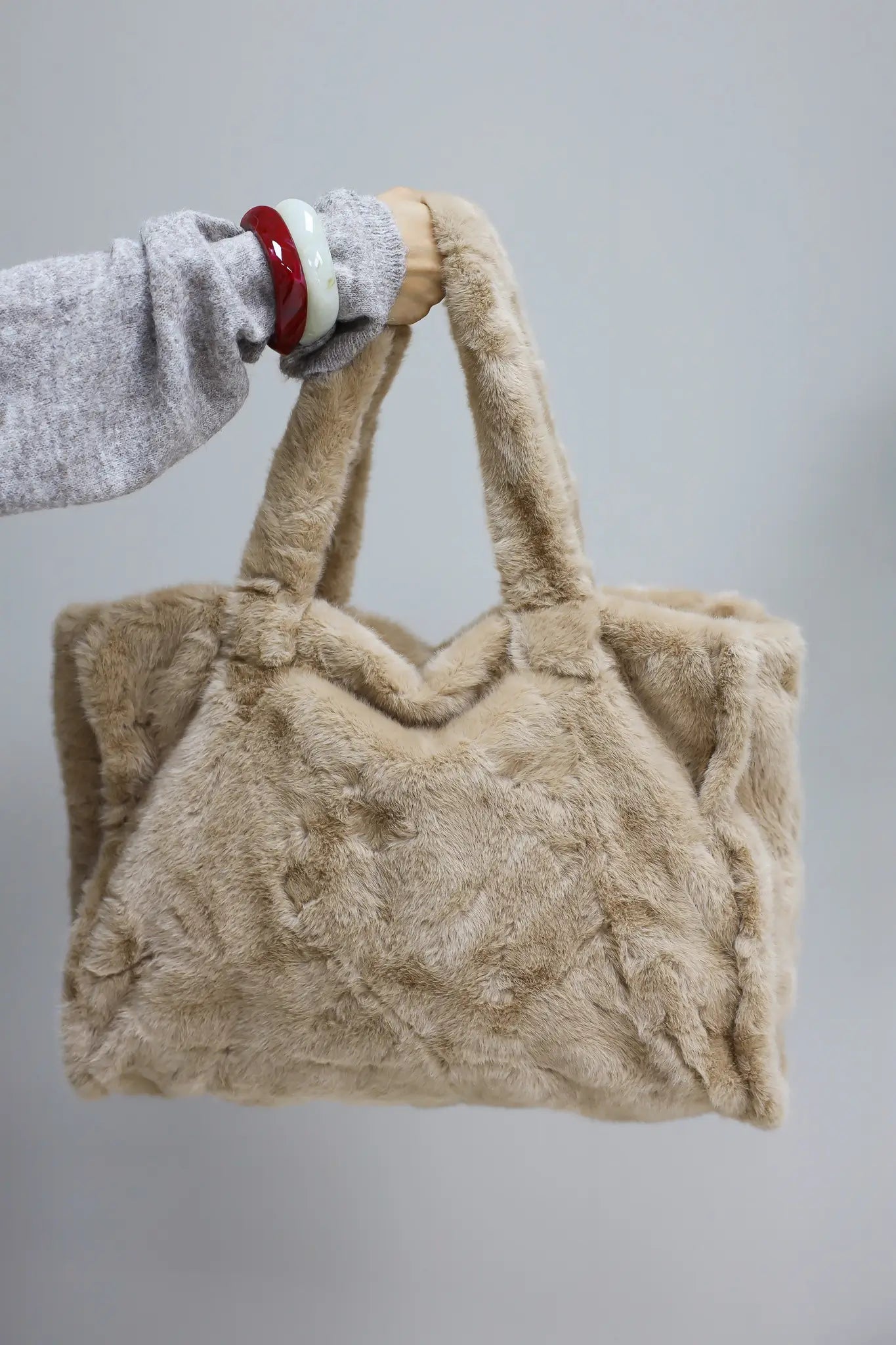 hand houdt camel faux fur shopper omhoog