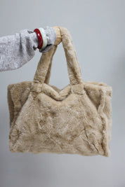 hand houdt camel faux fur shopper omhoog