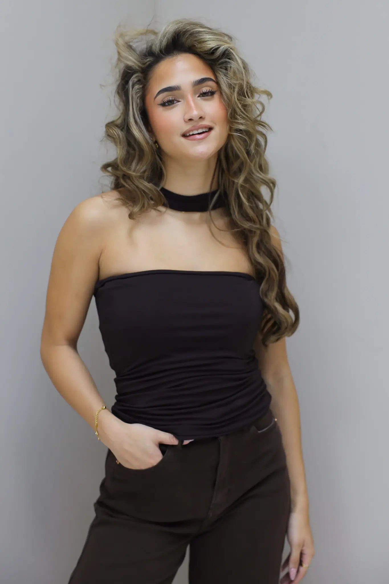 Model leunt licht tegen de muur met hand in zak en losse houding