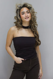 Model leunt licht tegen de muur met hand in zak en losse houding