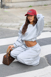Grijze comfy set met cropped sweater en wijde broek zittend op straat