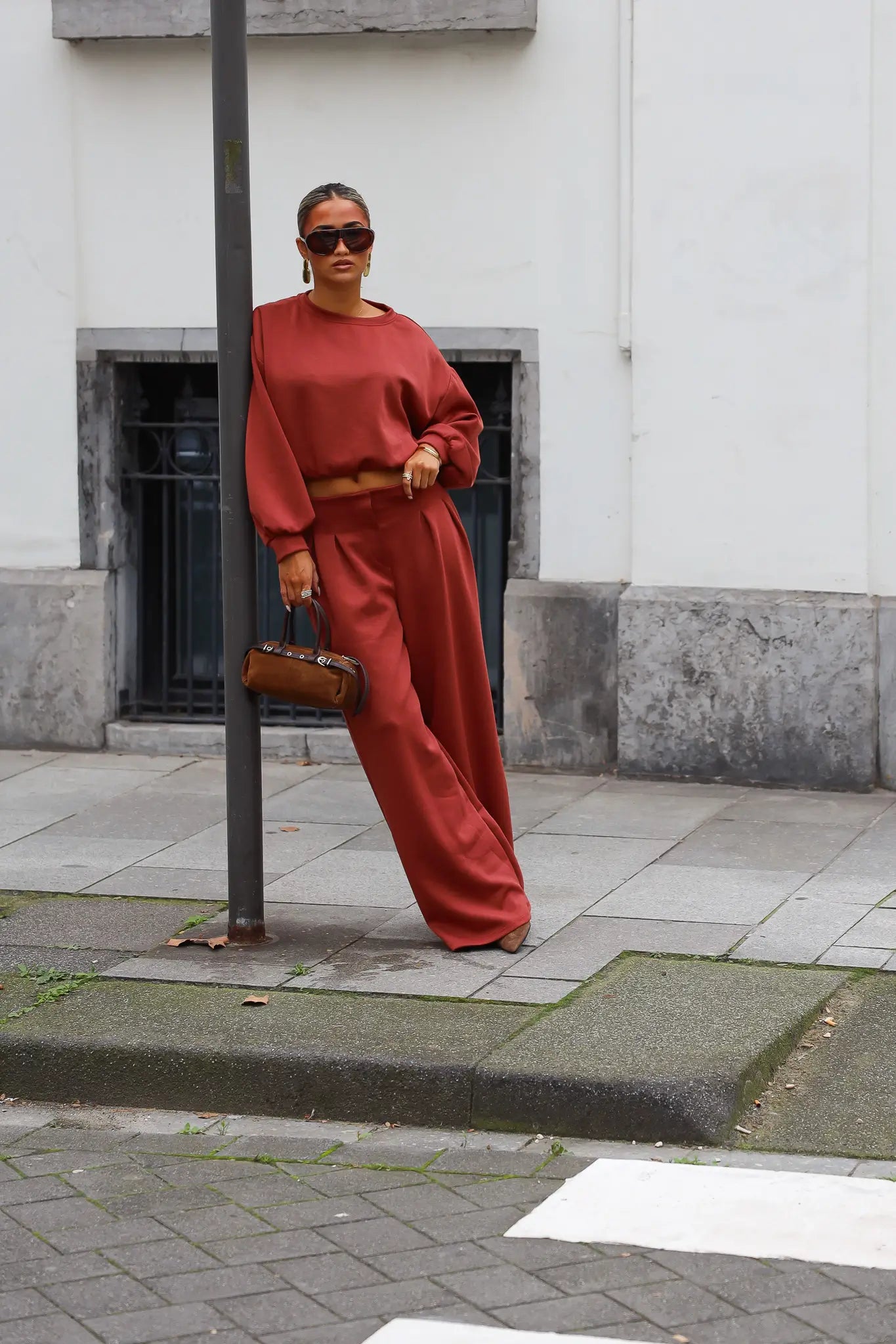 Terracotta tweedelige dames set met korte sweater en wijde broek gedragen met zonnebril
