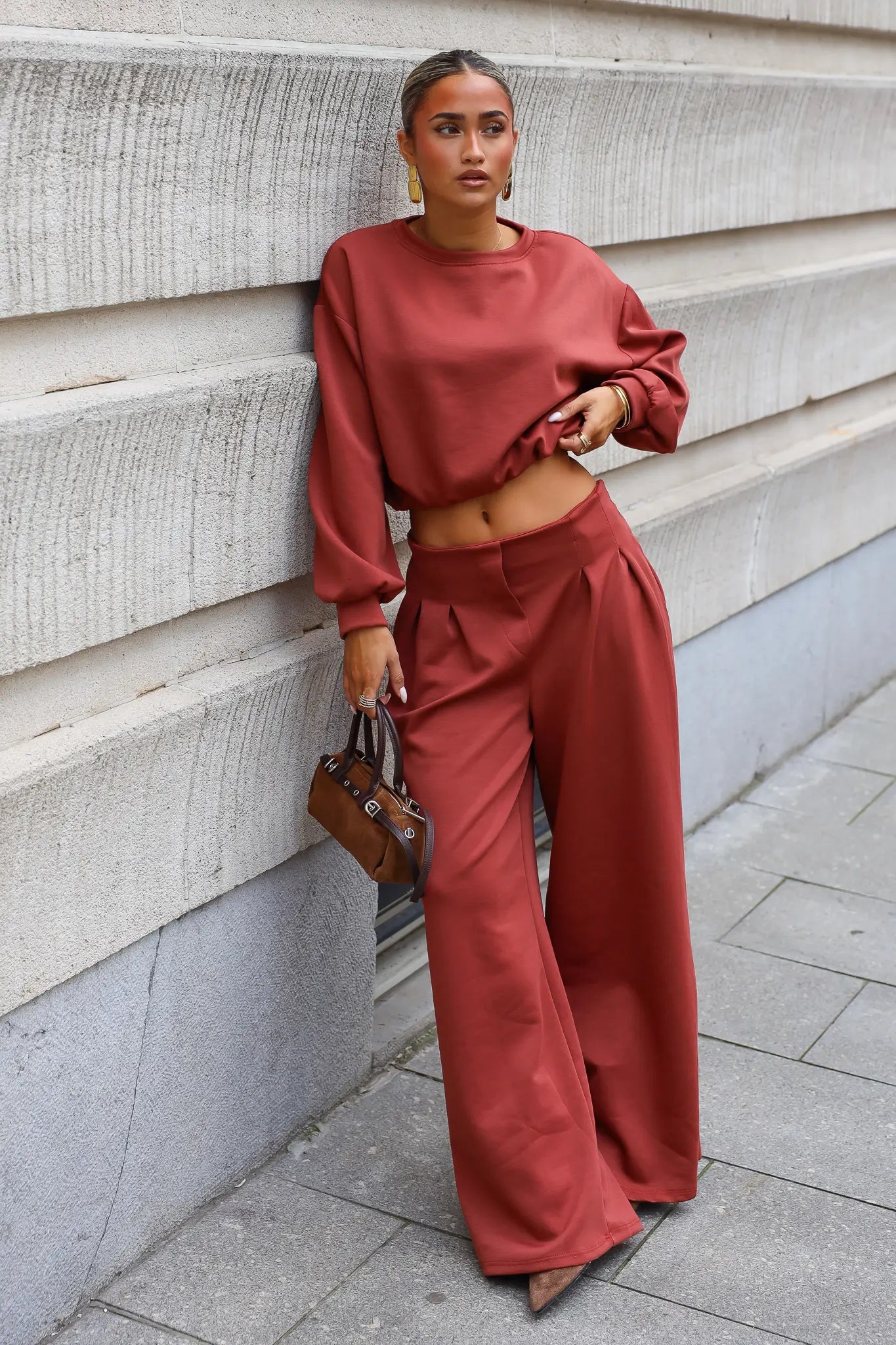 Terracotta comfy set met cropped sweater en wide leg broek gecombineerd met bruine handtas