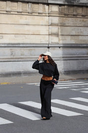 Zwarte tweedelige comfy set met sweater en wijde broek gedragen op straat