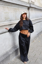 Zwarte comfy set met cropped sweater en wide leg broek gedragen met beige pet