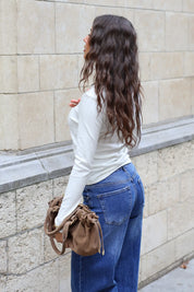 Rugaanzicht van crèmekleurig longsleeve shirt met aangesloten pasvorm en lange mouwen gecombineerd met blauwe jeans