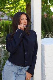 Model draagt blazer hand bij gezicht