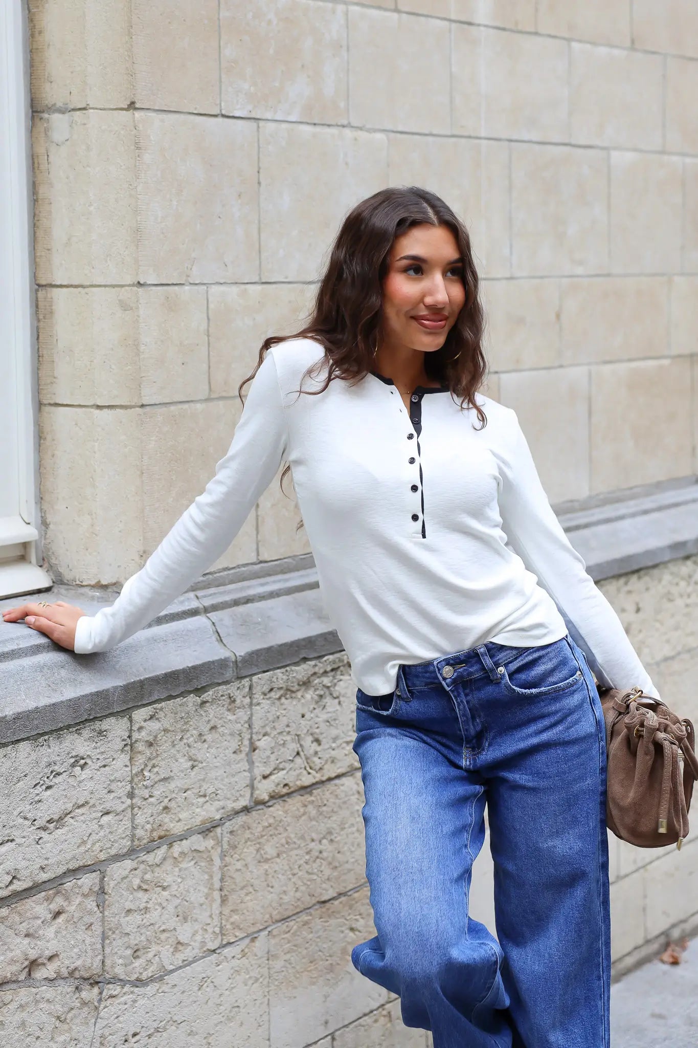 Crème dames longsleeve met zwarte knoopjes en contrasterende halsbies gecombineerd met blauwe wide leg jeans