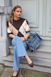 Denim schoudertas jeans blauw gedragen terwijl model zit