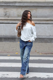 Donkerblauwe wide leg jeans met lichte denim wassing gedragen met een witte off shoulder longsleeve