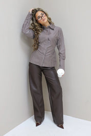 Model met fur jas en faux leather broek, tegen beige muur, handen in zakken