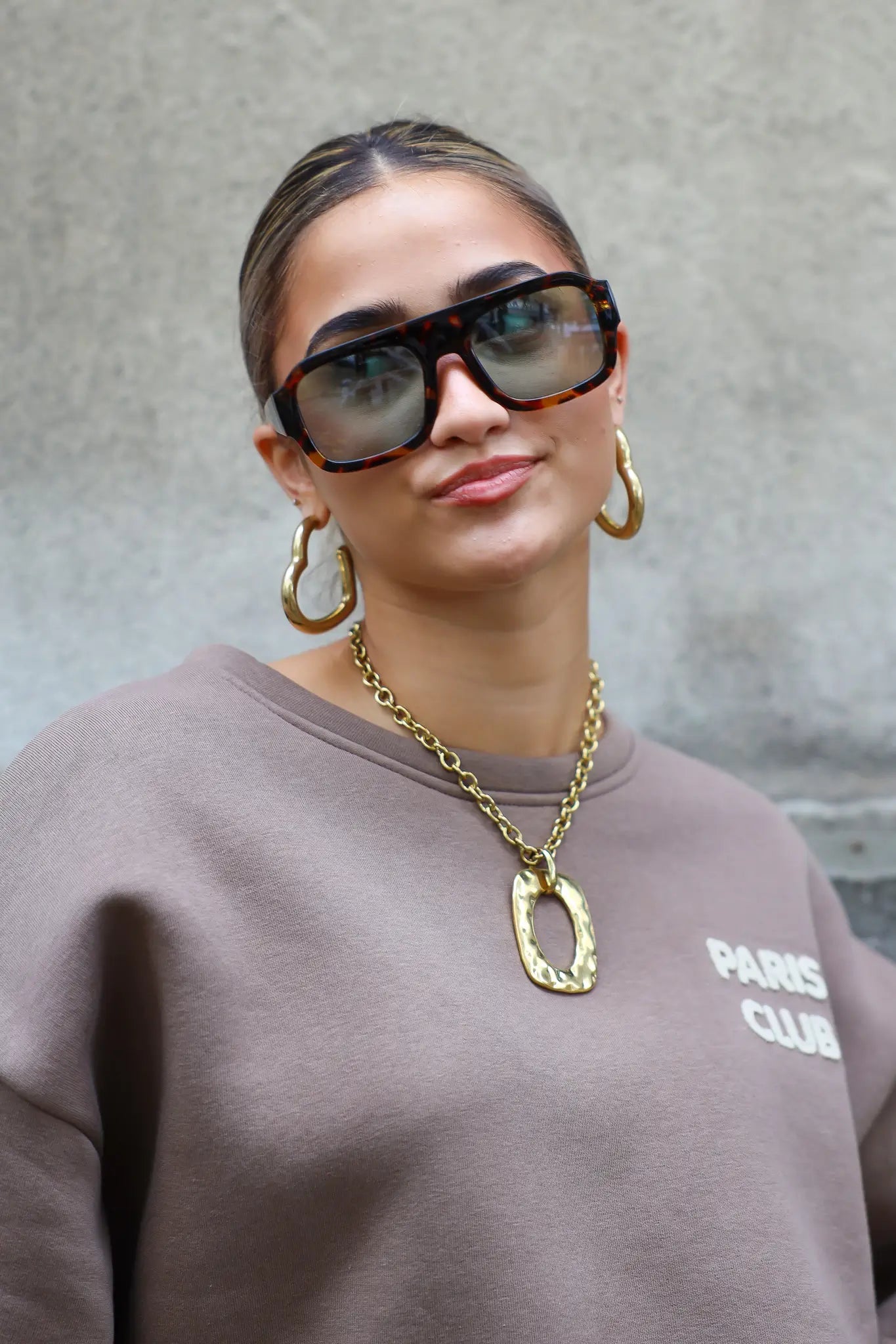 model met zonnebril kijkt recht vooruit en glimlacht licht