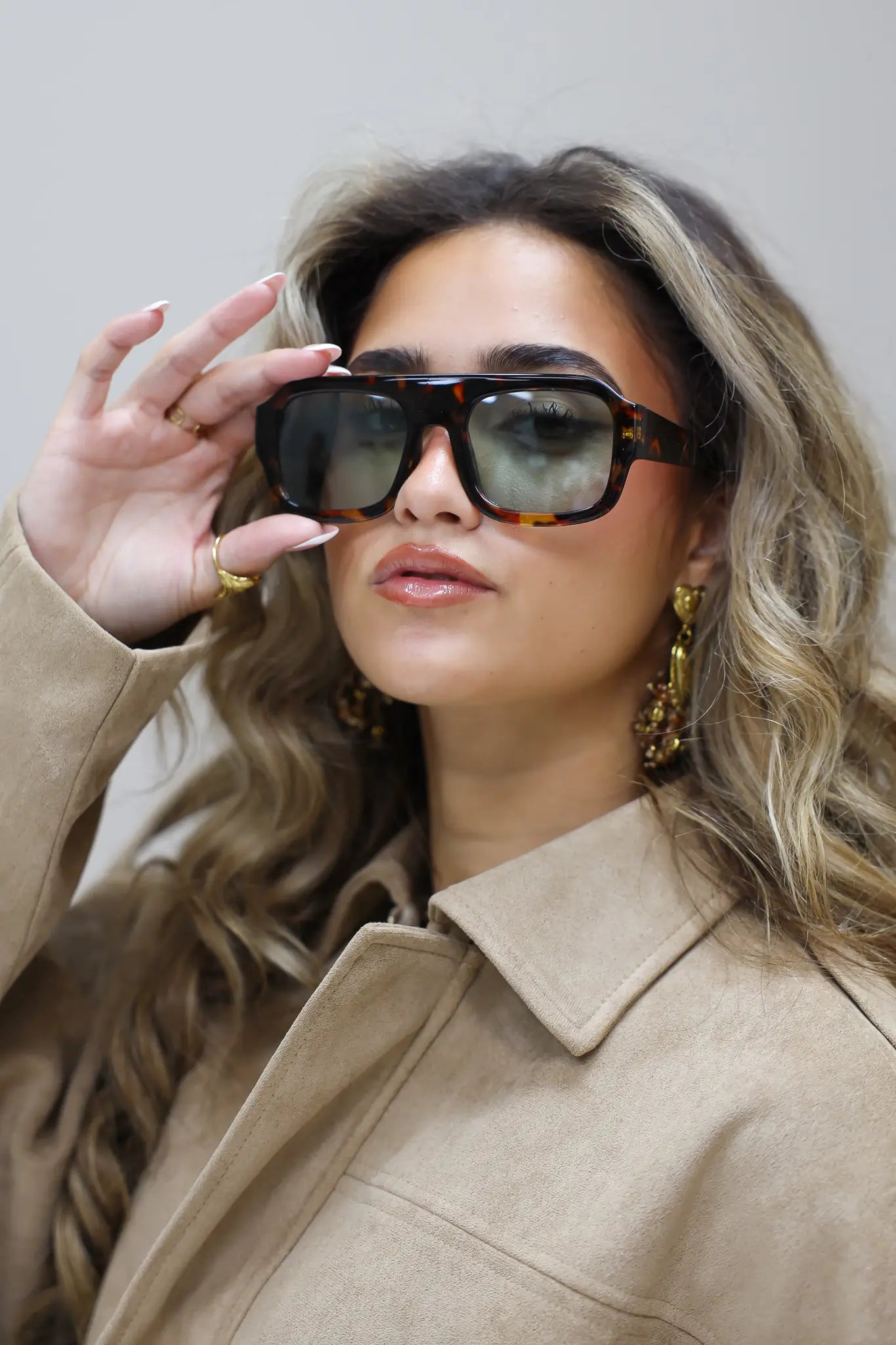 model in profiel met zonnebril en trui in taupe kleur