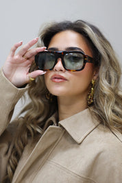 model in profiel met zonnebril en trui in taupe kleur