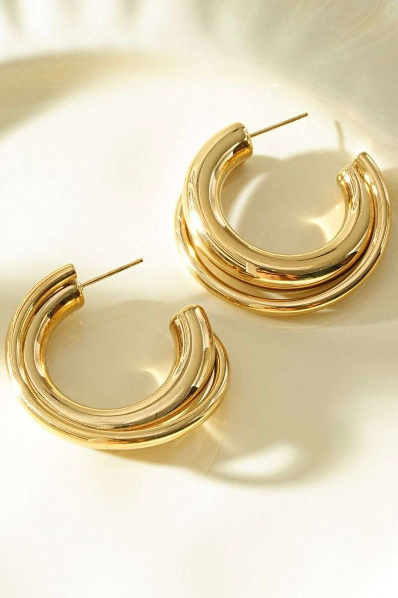 Dubbele goudkleurige oorringen op lichte achtergrond