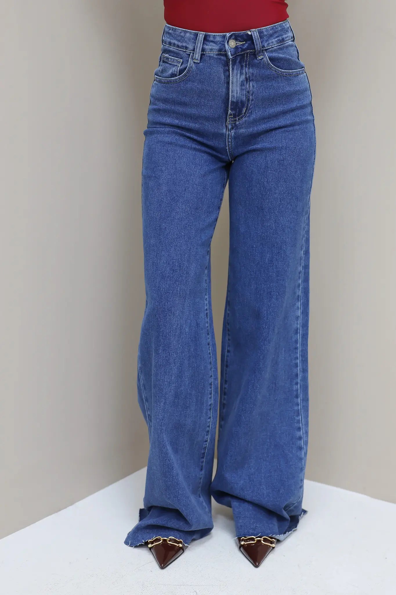 Jeans over de hele lengte zichtbaar, model in rode top met bruine tas