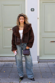 model loopt buiten met bruin faux fur jasje en jeans