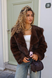 model staat buiten met bruin faux fur jasje en kleine tas