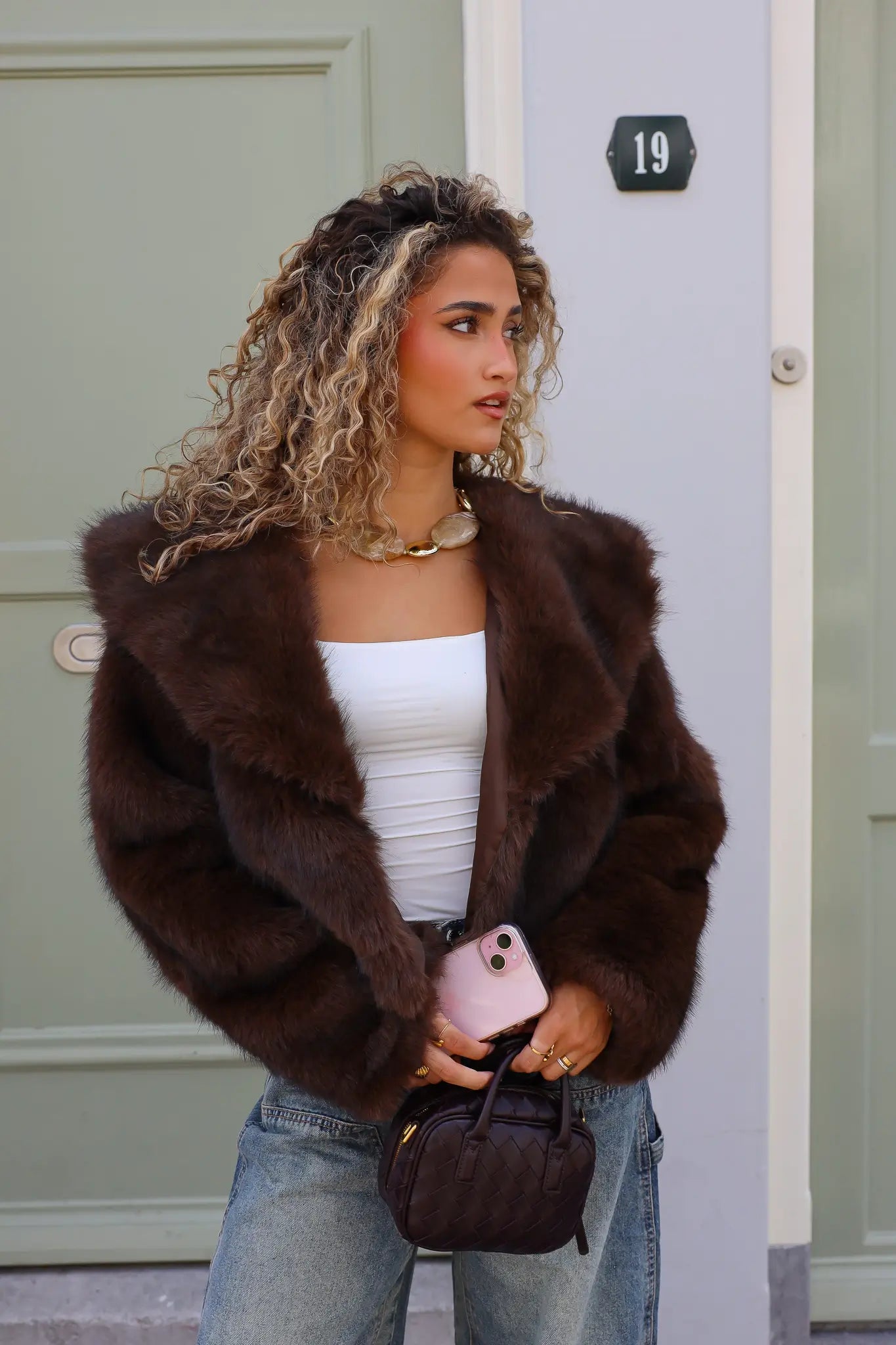 model buiten met faux fur jasje open over witte top