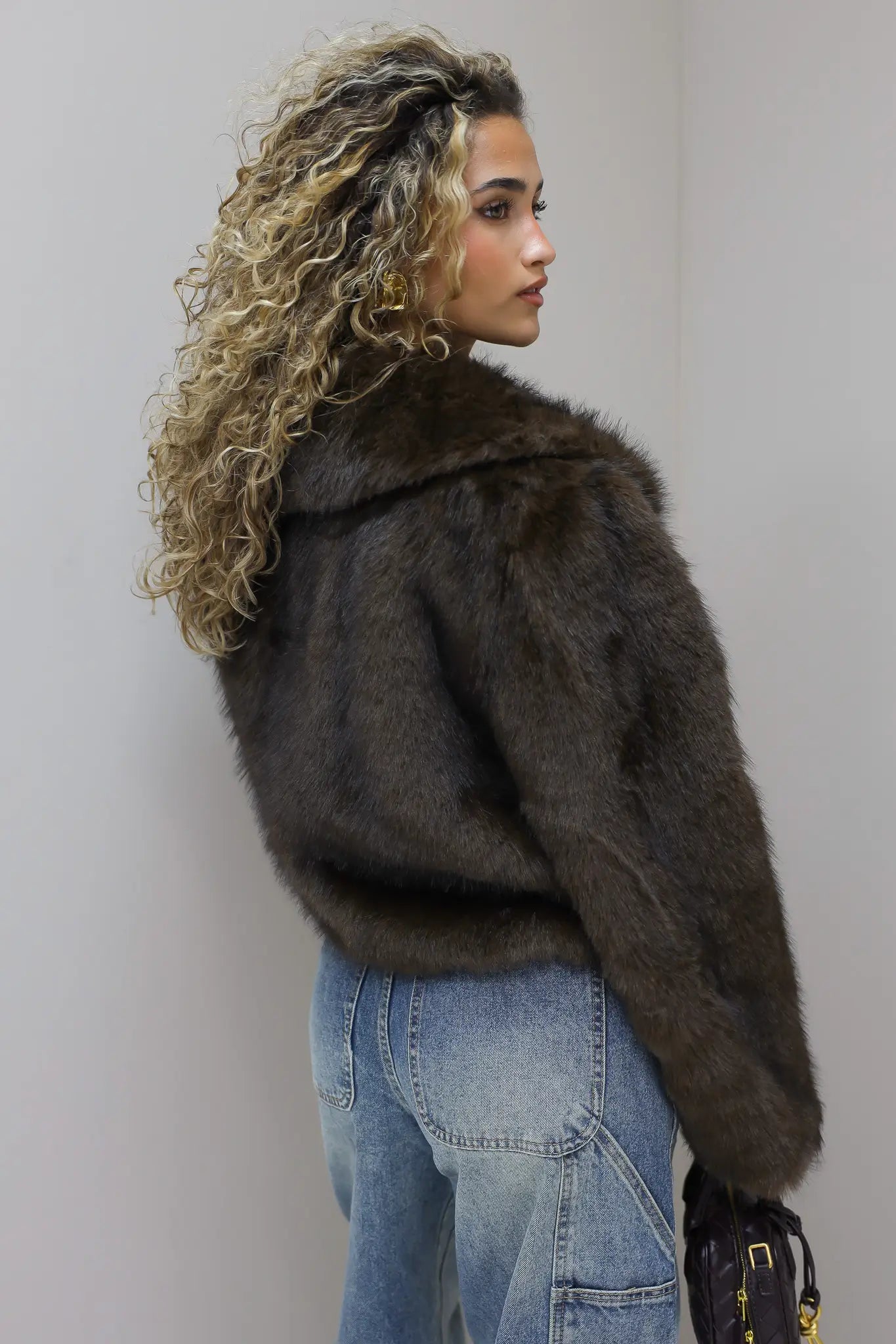 model draait licht weg met faux fur jasje in studio