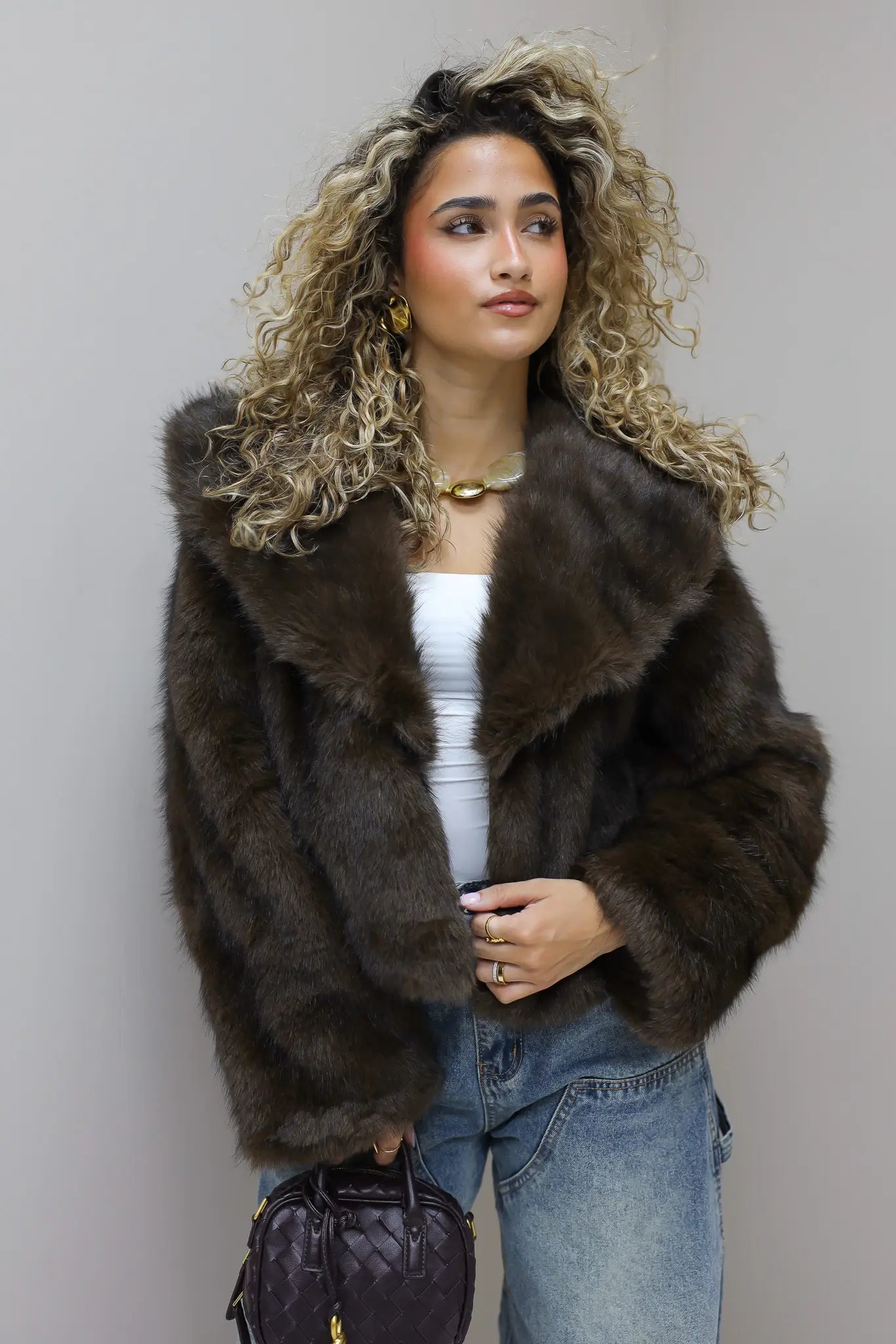 model draagt bruin faux fur jasje in studio van voren