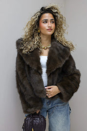 model draagt bruin faux fur jasje in studio van voren