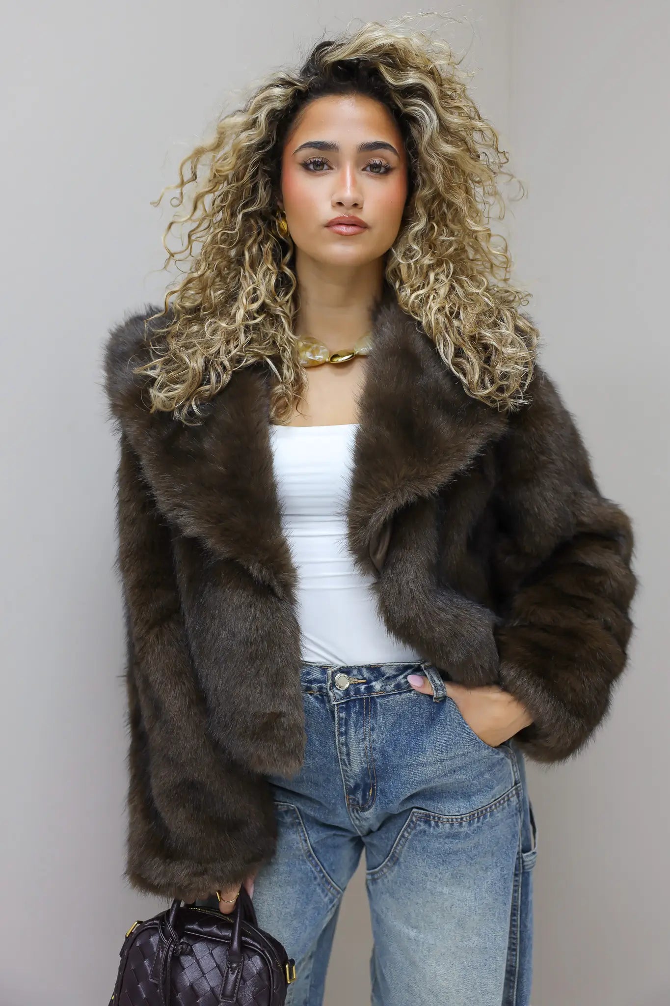 model draagt faux fur jasje in studio voor beige achtergrond