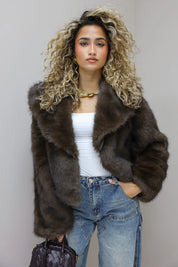 model draagt faux fur jasje in studio voor beige achtergrond