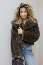 model staat in studio met bruin faux fur jasje en jeans
