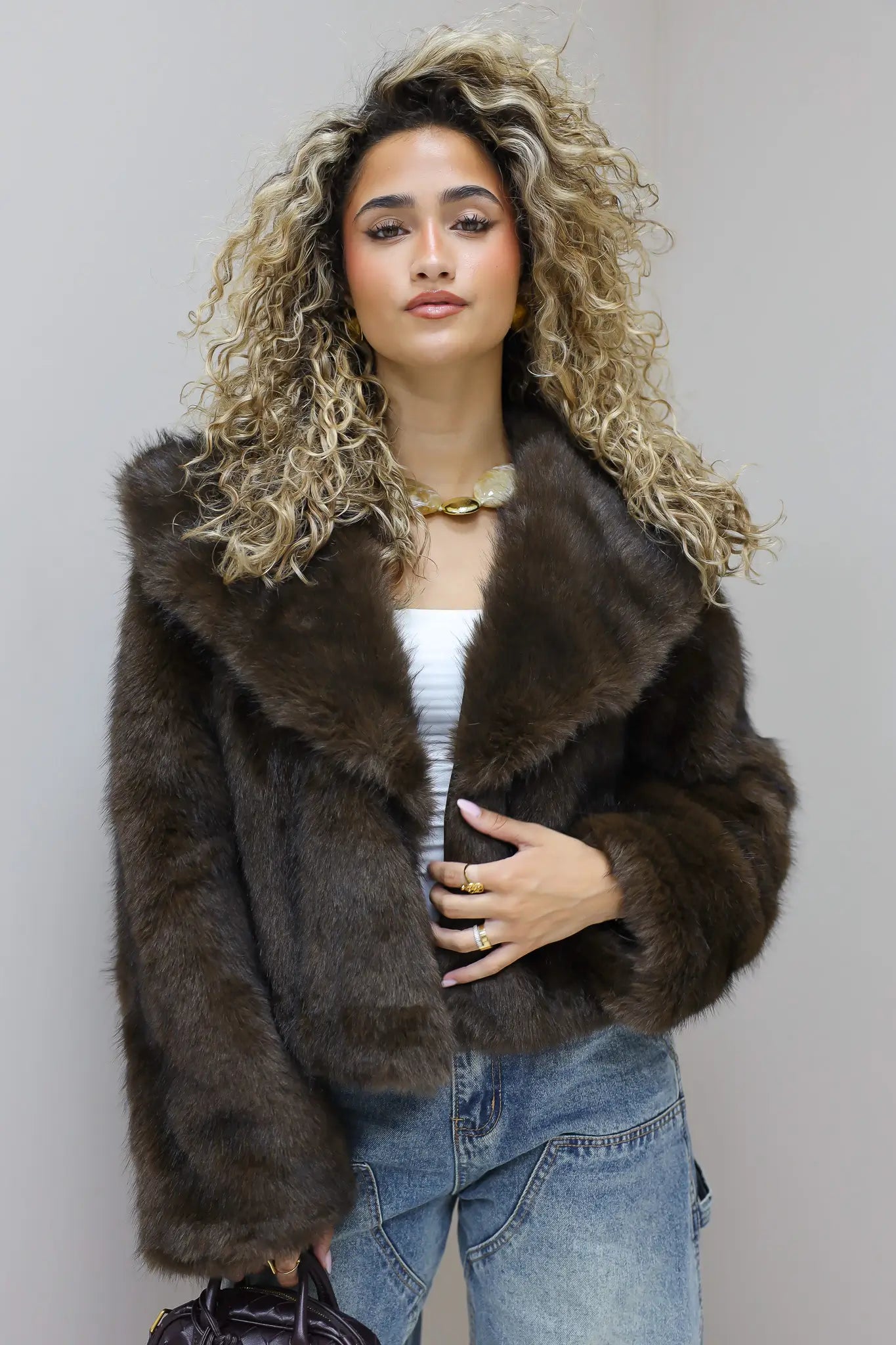model zit rechtop in faux fur jasje en jeans