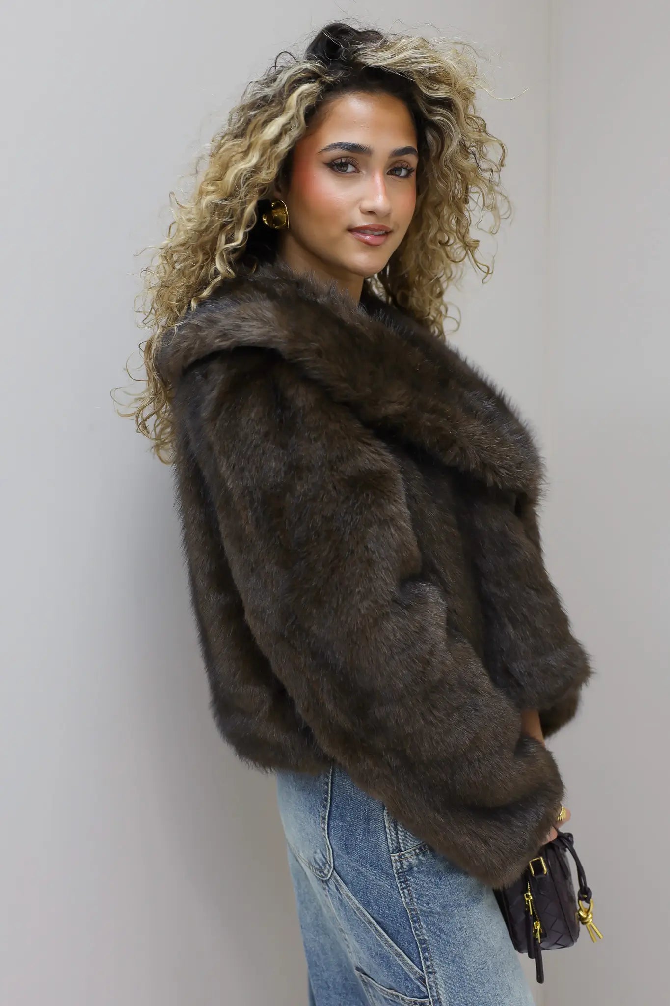 model staat zijwaarts met bruin faux fur jasje en handtas