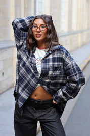 Model draagt een oversized donkerblauwe flanellen blouse met ruitjes, losjes gestyled over een crème shirt.