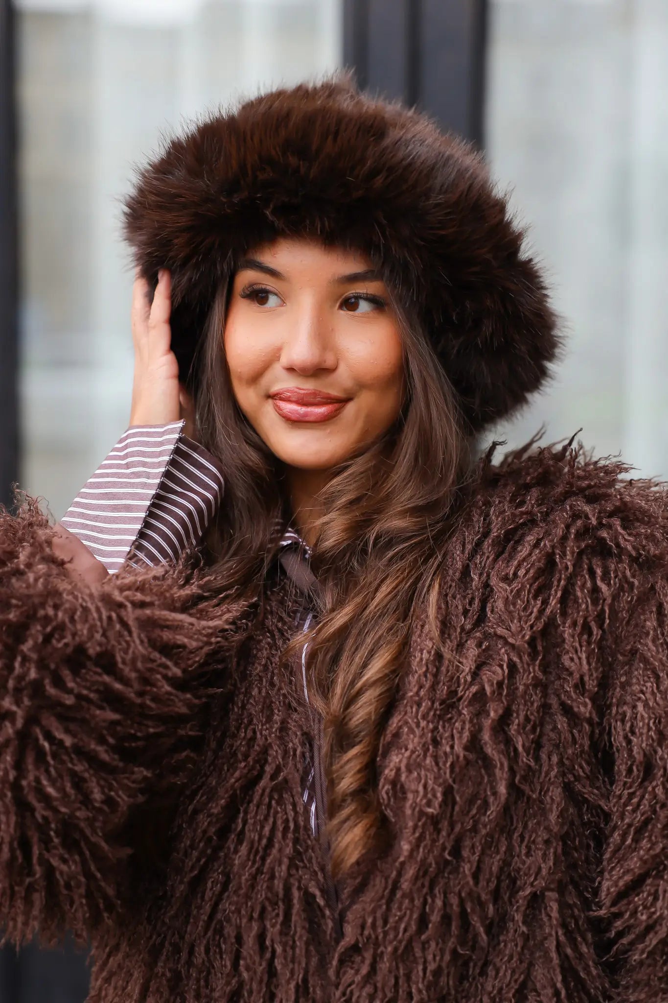 Model kijkt recht in de camera met fluffy muts bruin