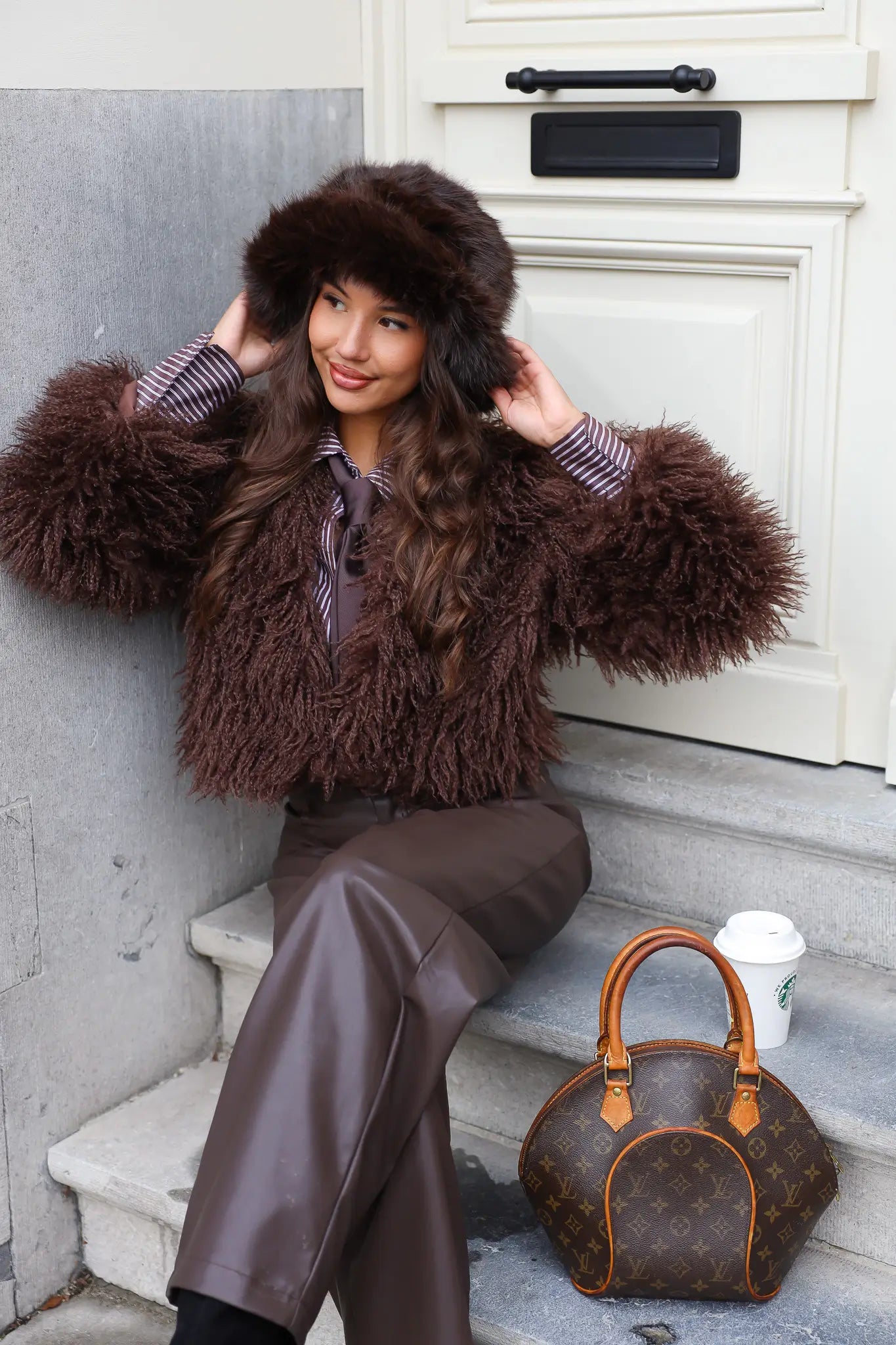 Model draagt fluffy muts met bruine jas en tas