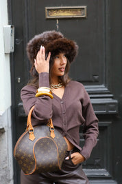 Model houdt tas vast terwijl ze fluffy muts bruin draagt