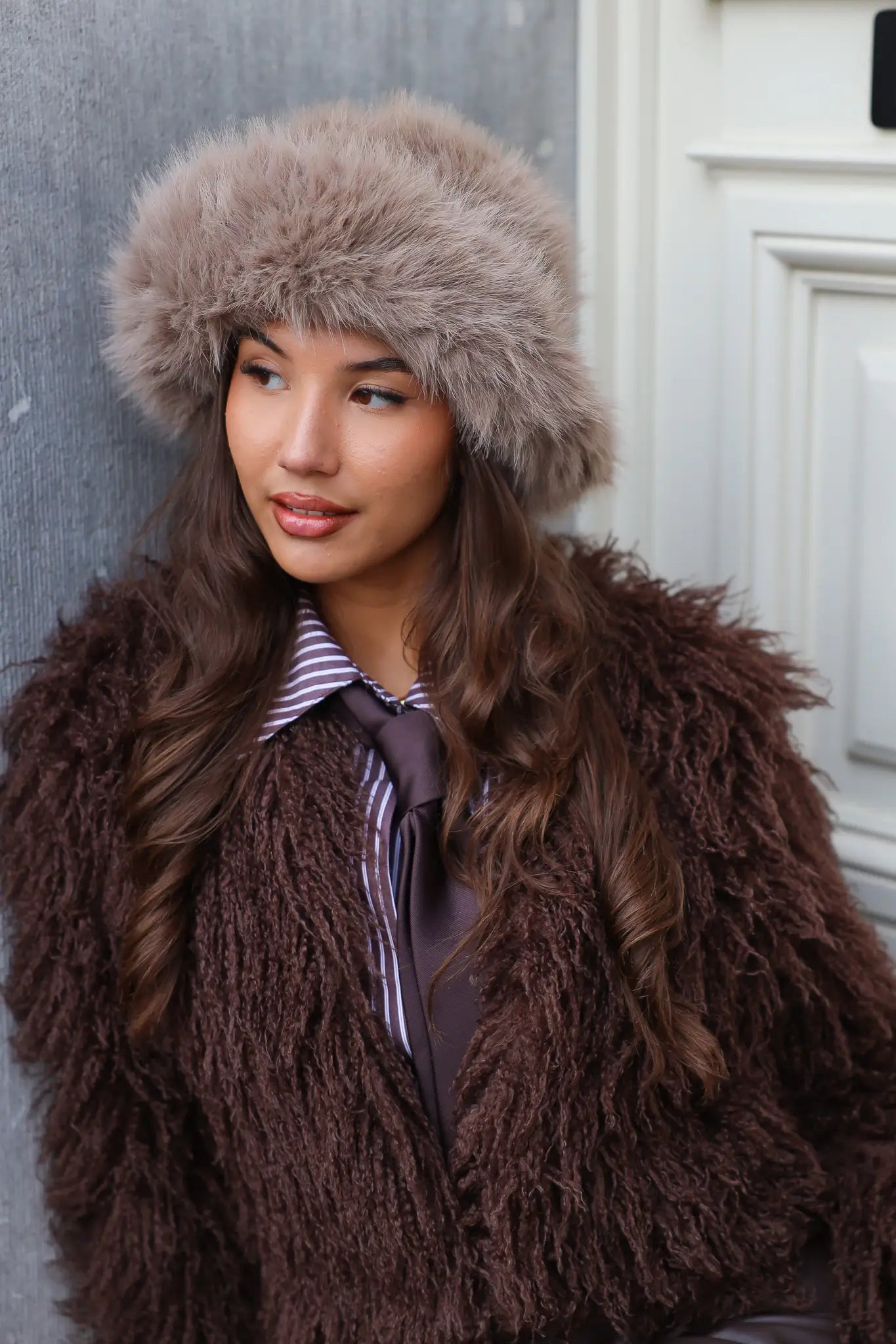 Model kijkt in de camera met taupe fluffy muts