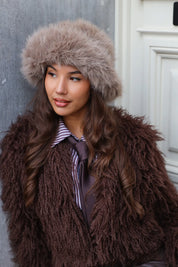 Model kijkt in de camera met taupe fluffy muts