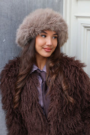 Totale outfit met taupe fluffy muts, bruine jas en leren tas