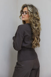 model staat half gedraaid naar achter, vest dichtgeknoopt met zicht op taillering