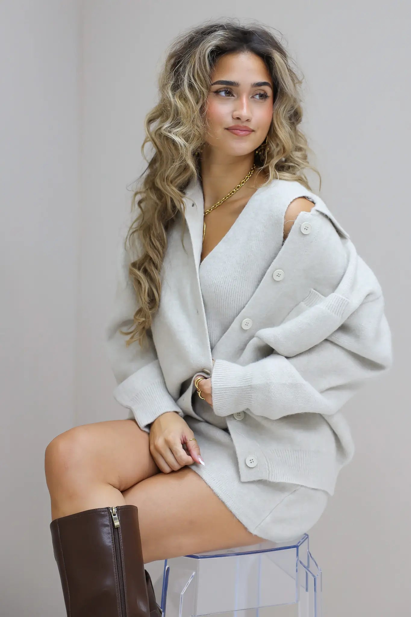 gebreide vest beige dames vest knopen kort model zittende studio foto close up zijkant