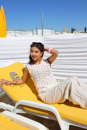 Model draagt gehaakte top roze op strandstoel