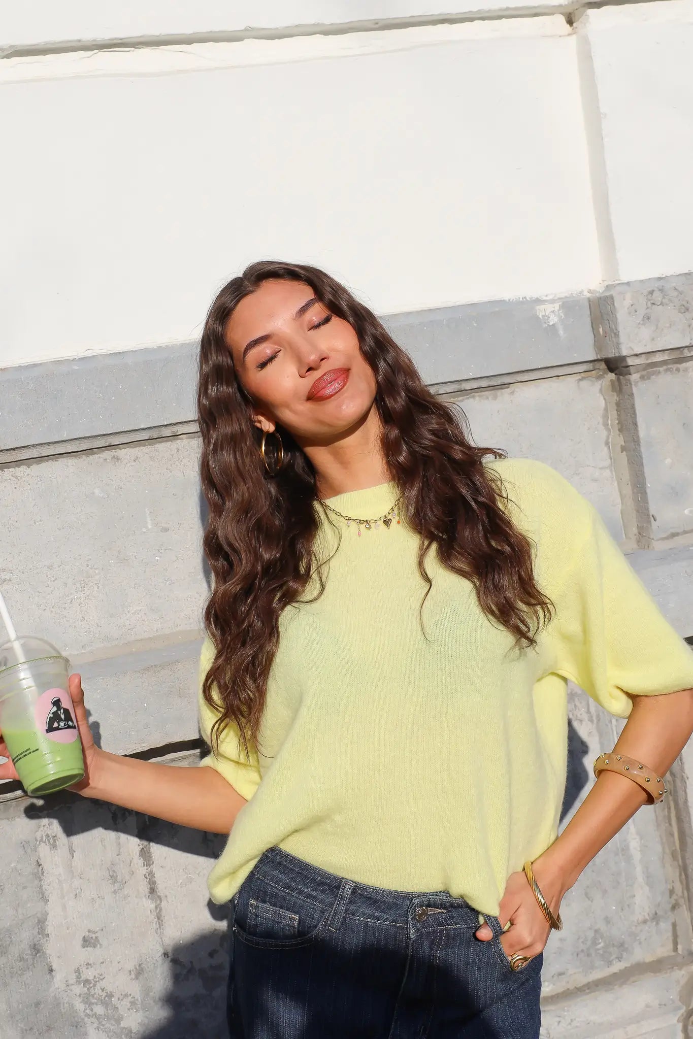 model draagt gele trui met donkere jeans dames ladylike