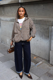 Geruite blouse met capuchon in camel en bruin gecombineerd met donkere wide leg jeans en bruine handtas