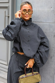 Close-up van zwarte geruite windbreaker met volumineuze mouwen en opstaande kraag