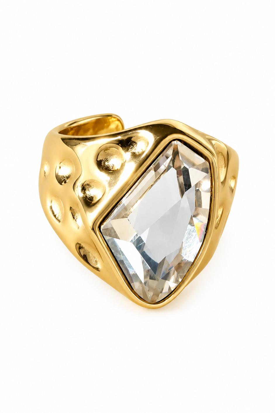 Gouden statement ring met grote transparante steen en brede band met bolvormige details op witte achtergrond
